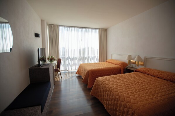 A hotel room with two beds, a desk with a TV, a chair, and a window with curtains. - Hotel San Francisco Toluca (Toluca)