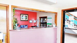 A hotel reception area with a red wall, a reception desk, a calendar, and a plant. - Courtesy Inn (Oklahoma City)