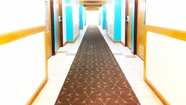 A hotel corridor with wooden handrails, blue doors, and a patterned carpet. - Courtesy Inn (Oklahoma City)