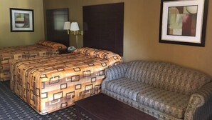 Une chambre d’hôtel avec un grand lit, un canapé, une petite table et deux tableaux encadrés accrochés aux murs.