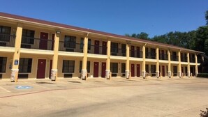 Un motel avec une rangée de chambres, chacune dotée d’une porte et de fenêtres.