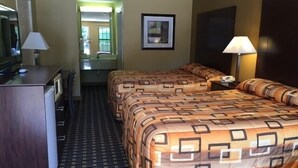 Une chambre d’hôtel avec un lit, un bureau, une chaise, une lampe et un tableau encadré au mur.