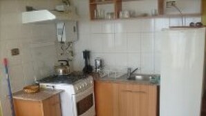 A compact kitchen with a stove, sink, and wooden cabinets.