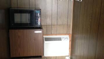 A compact room with a bunk bed, a microwave, a small refrigerator, and a heater.