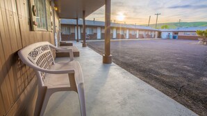 A motel with a covered parking area, a row of rooms, and a bench outside. - Dayton Motel (Dayton)
