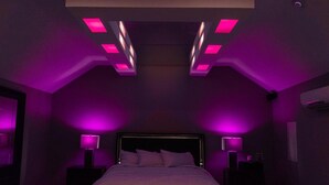 Une chambre à coucher avec un lit, des tables de chevet et un luminaire au plafond.