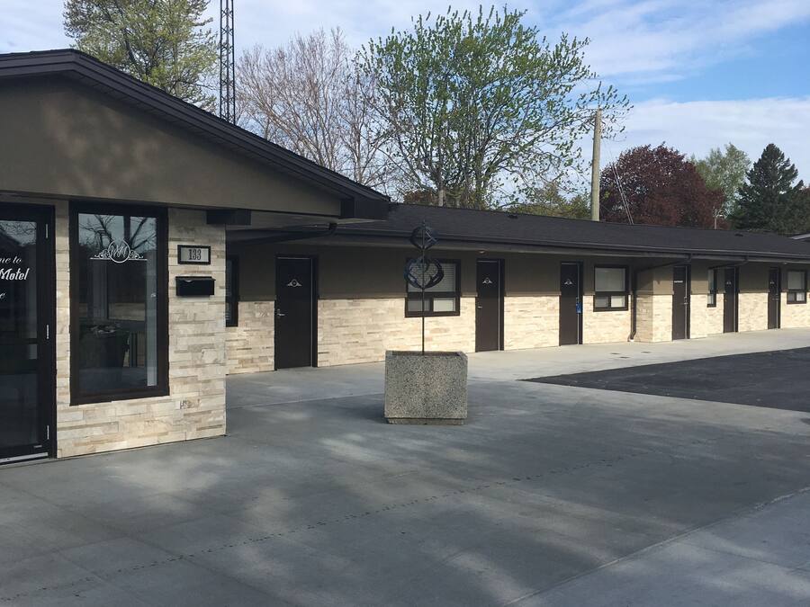 A motel with a simple facade, multiple rooms, and a parking lot.