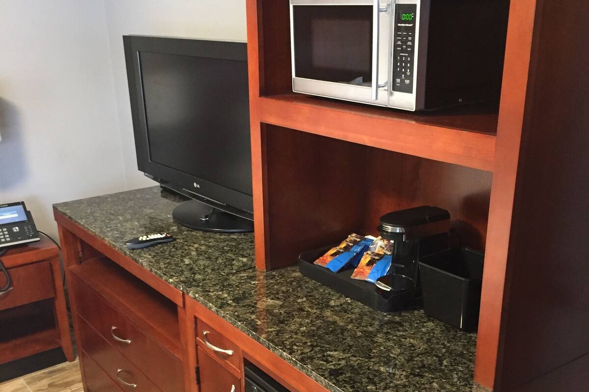 Una cocina compacta con microondas, un refrigerador negro y encimera de granito.