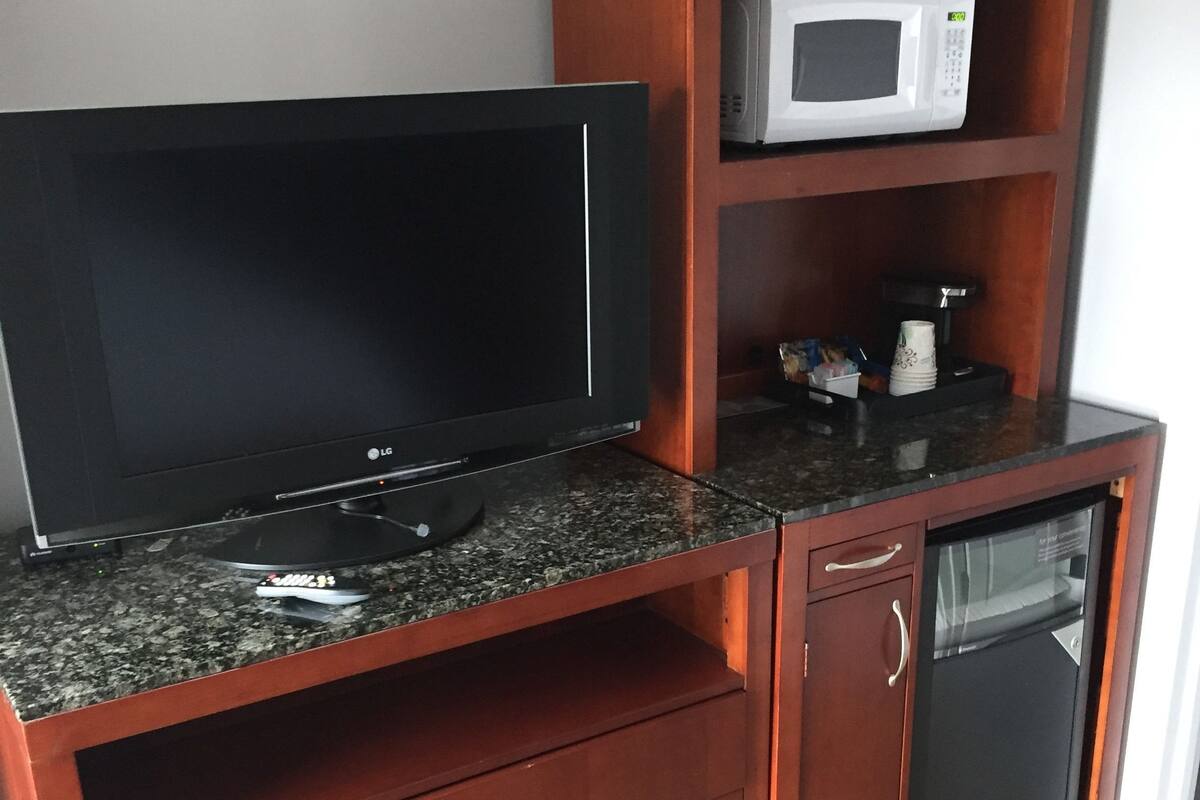 Un mueble de madera con un televisor de pantalla plana, un microondas y un refrigerador pequeño.