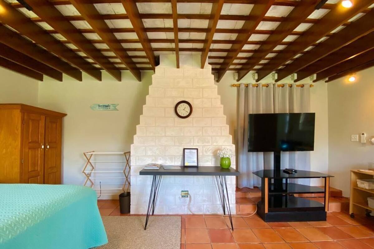 Une pièce confortable avec un lit, une télévision, une cheminée et un plafond en bois.