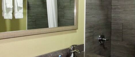 A bathroom with a sink, mirror, and shower.