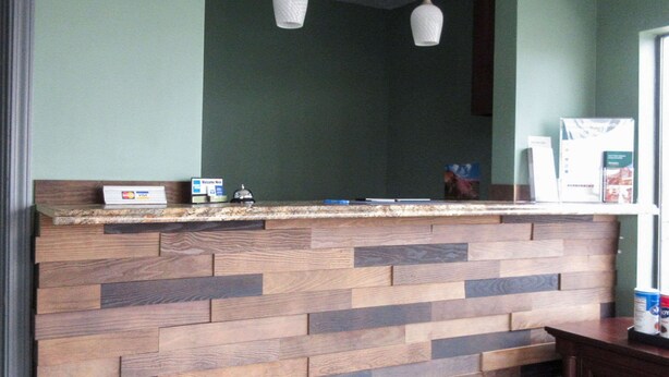 Un espace d’accueil avec un mur recouvert de panneaux en bois, un comptoir doté d’un lecteur de cartes et une fenêtre avec des stores.