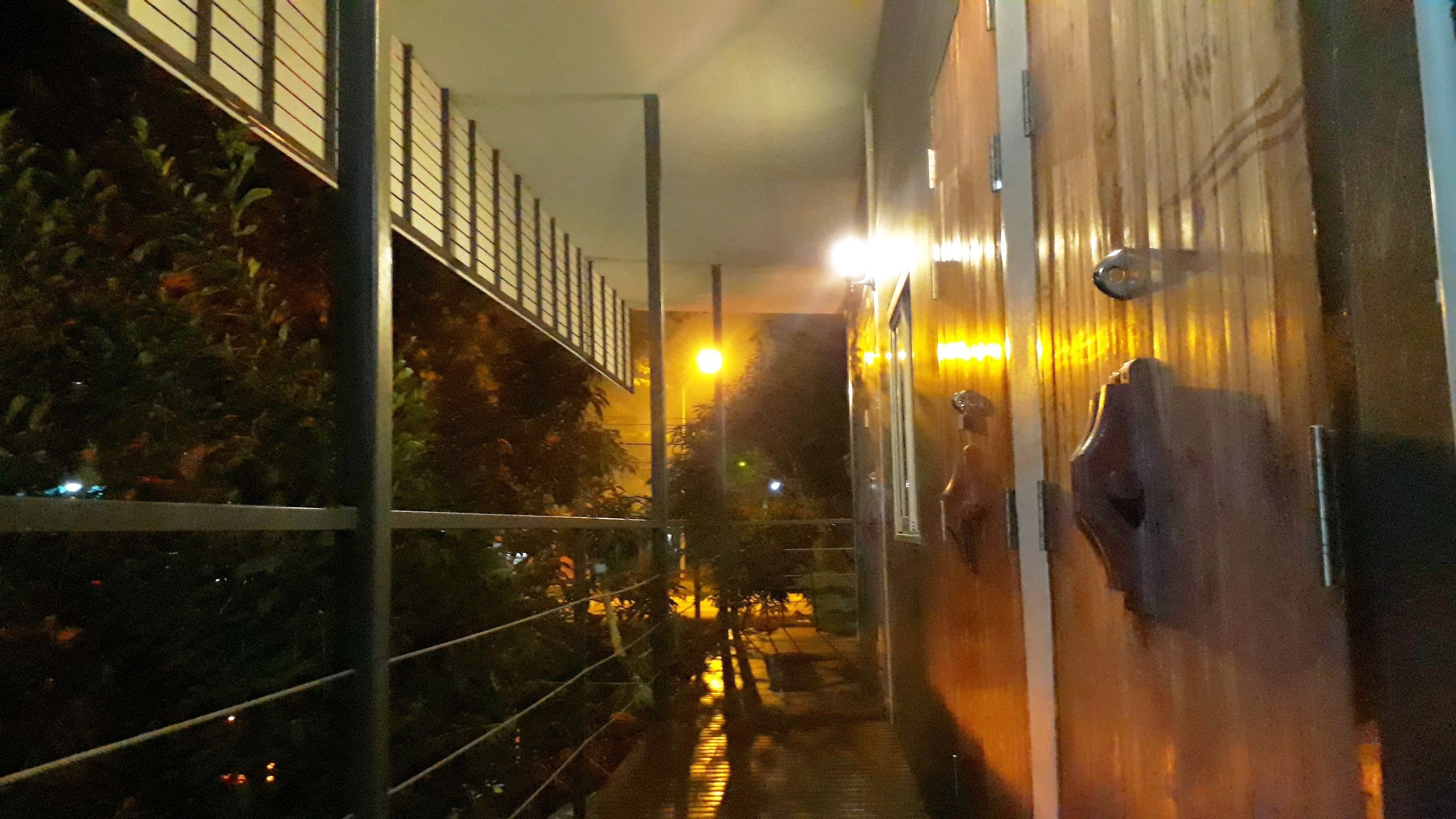 A corridor with a metal railing, a wet floor, and a door with a wooden panel.