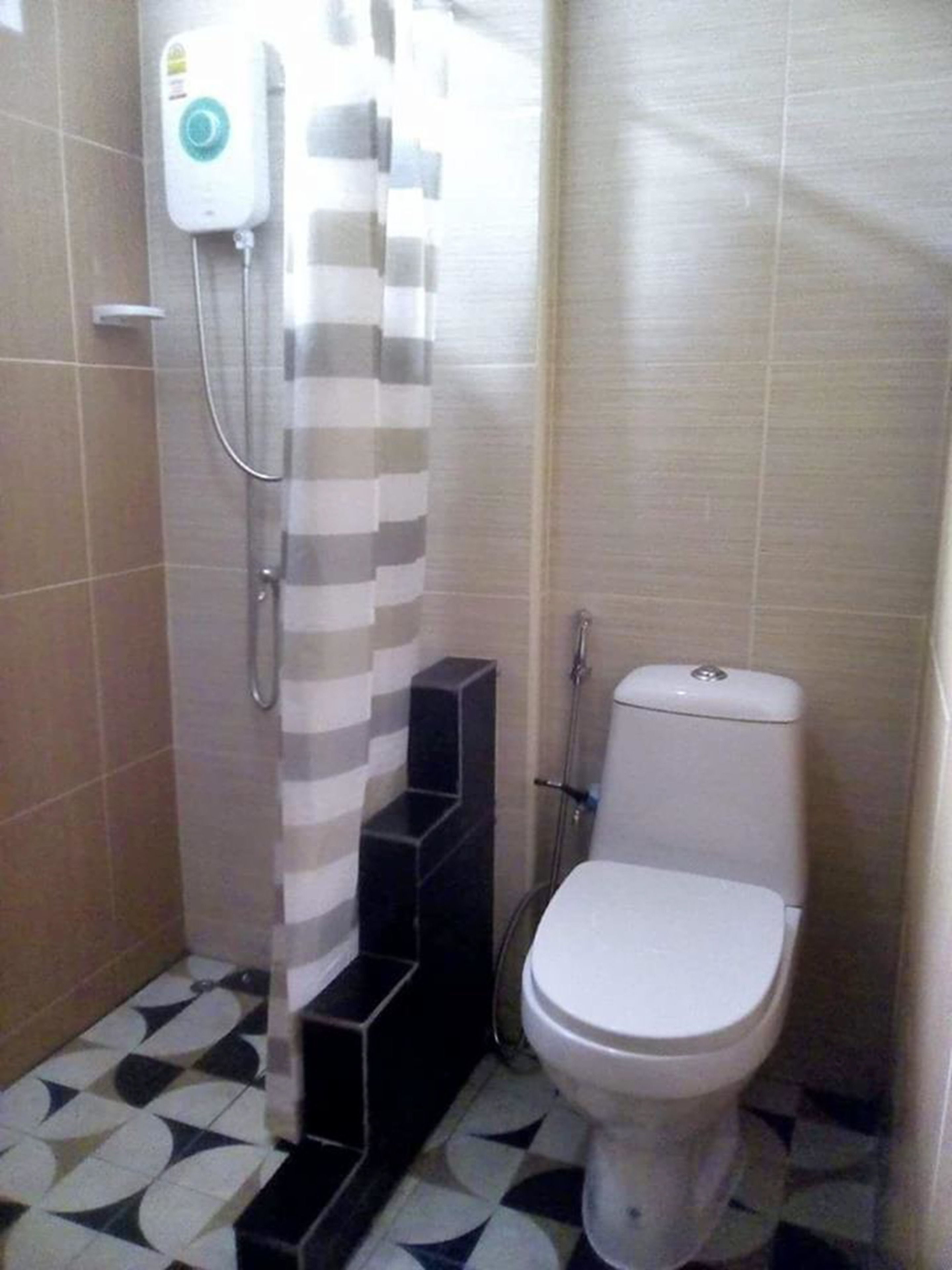 Une petite salle de bain comprenant des toilettes, une douche et un sèche-mains.