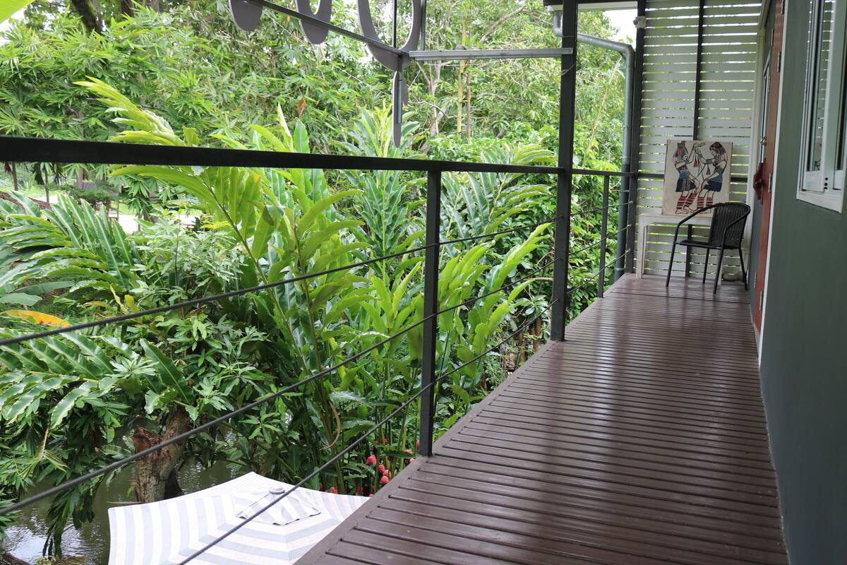 A wooden deck with a metal railing overlooking a lush garden.