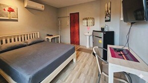 Una camera d'albergo con un letto, una scrivania, una TV e un condizionatore d'aria.