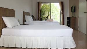 A large bed with white bedding, a wooden headboard, and a small bedside table with a lamp. - White Coral Hotel (Boracay Island)