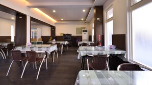A restaurant with multiple tables and chairs, a television, and a refrigerator. - Wogo Hotel (Yilan)