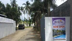 A road leading to a hotel with a sign indicating it is now open. - Shore Time Hotel Javier Leyte (Javier)