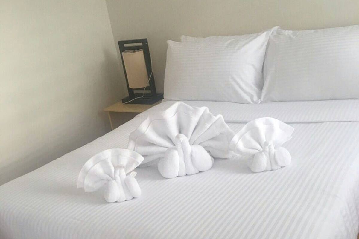 A neatly made bed with white linens and a wooden headboard.