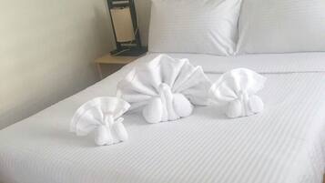 Una cama bien tendida con sábanas blancas y un cabecero de madera.