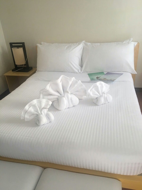 A neatly made bed with white linens and decorative towels arranged in a fan shape. - Shore Time Hotel Javier Leyte (Javier)