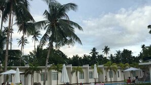 A resort with outdoor seating and palm trees. - Shore Time Hotel Javier Leyte (Javier)