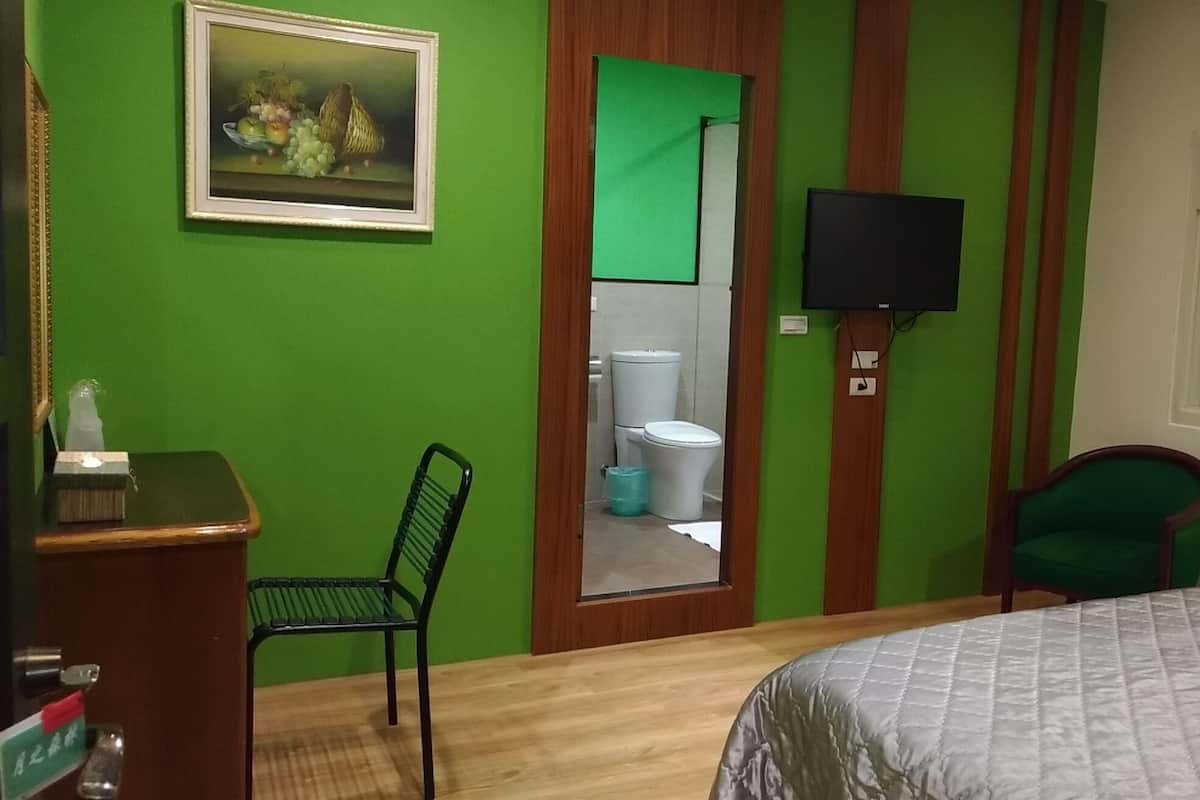 Ein Zimmer mit einem Bett, einem Schreibtisch, einem Sessel, einem Fernseher und einem Bild an der Wand.