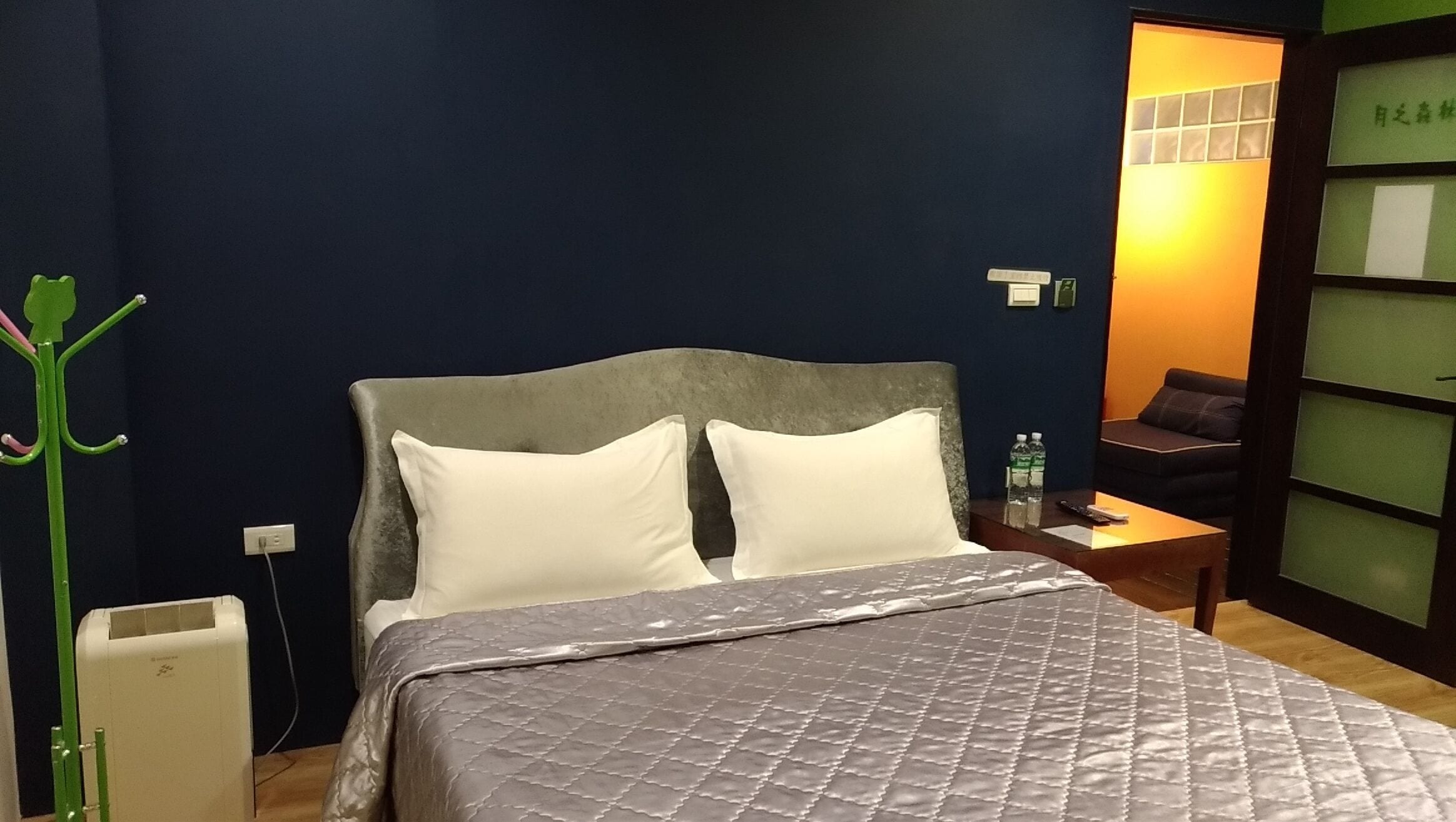 A hotel room with a bed, bedside table, and a nightstand.