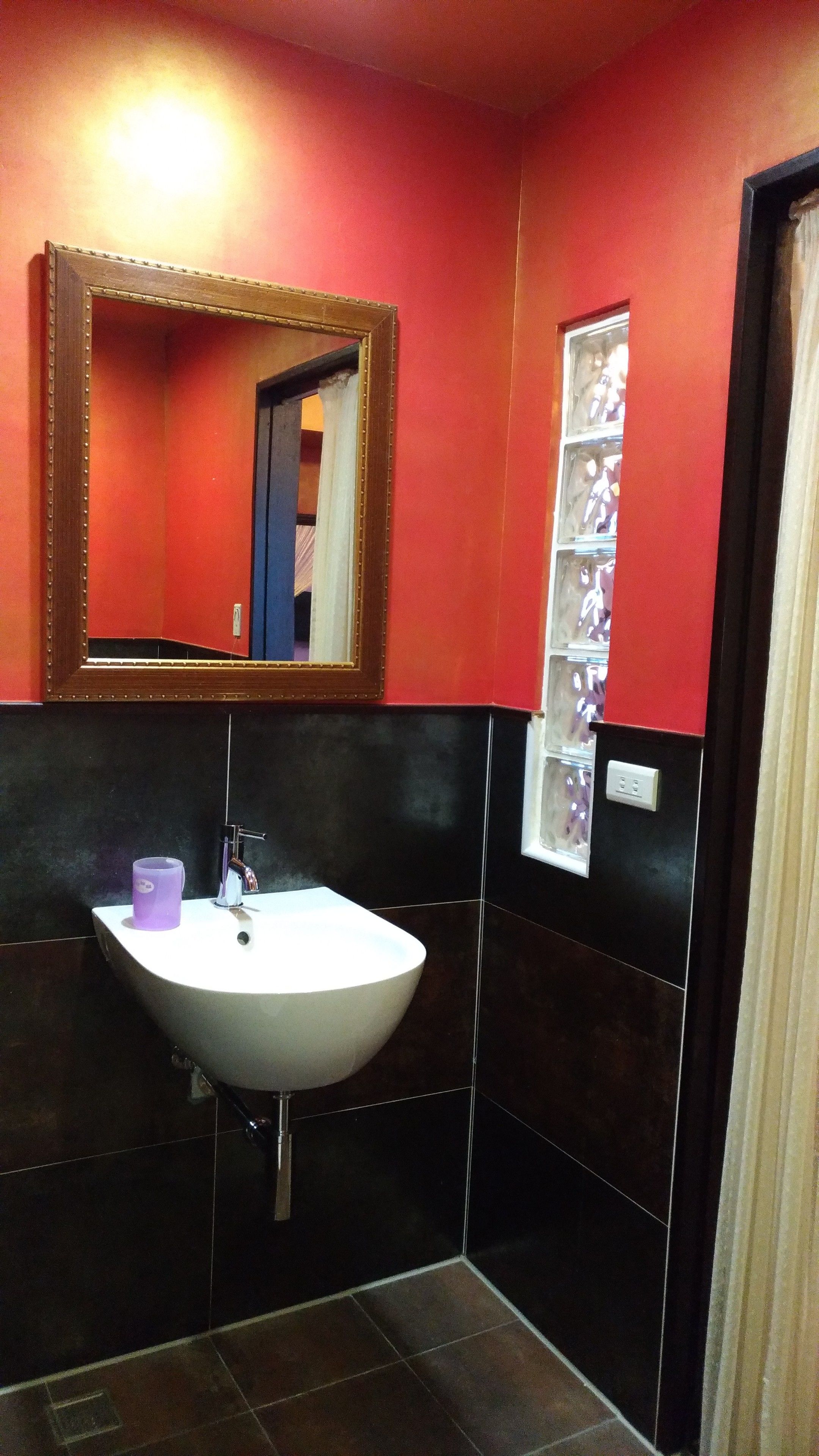 A bathroom with a white sink, a mirror, and a shelf with toiletries.
