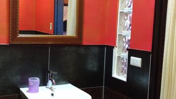 A bathroom with a white sink, a mirror, and a shelf with toiletries.