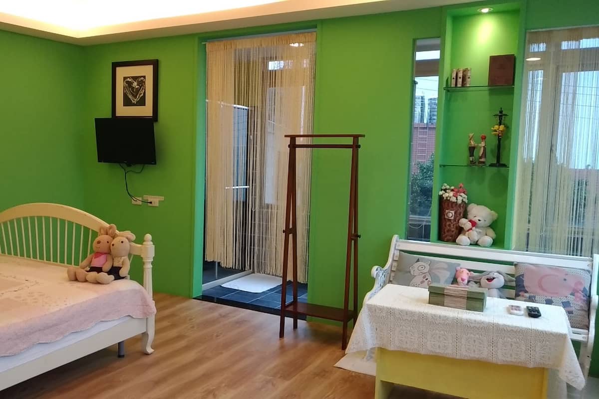 Ein Zimmer mit einem Bett, einem kleinen Tisch mit Spiegel, einem Fenster mit Vorhängen und einer grünen Wand.