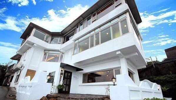 Una casa moderna de dos pisos con ventanas grandes y un balcón.