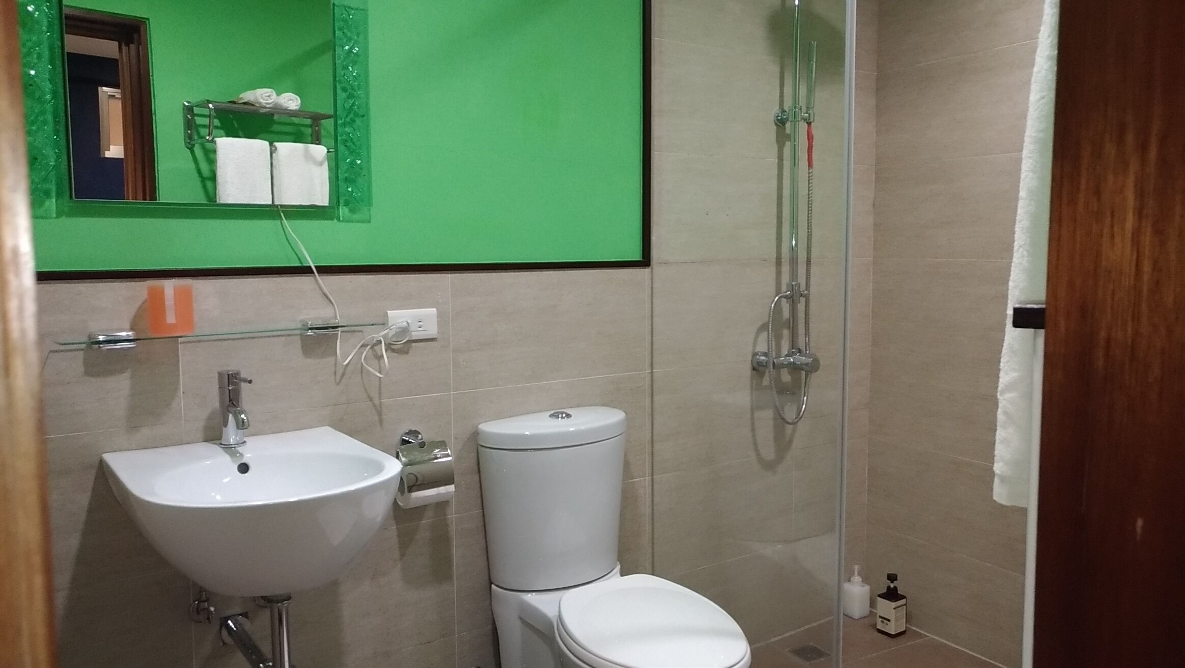 Et badeværelse med hvid vask, toilet og brusekabine med glasvægge.