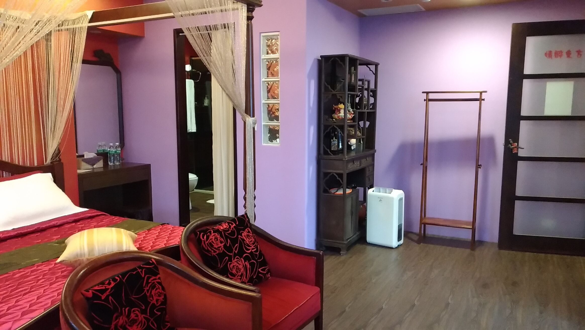 A bedroom with a canopy bed, a wardrobe, a mirror, and a door.