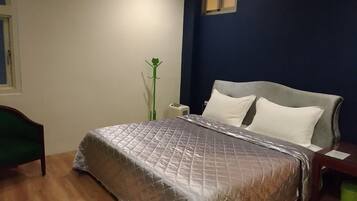 A bedroom with a bed, a nightstand, a lamp, and a window.
