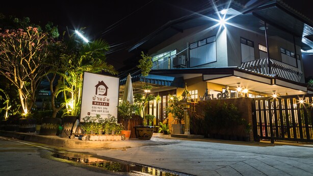 A well-lit hostel with a signboard, potted plants, and a gated entrance. - Banchan Hostel (Ayutthaya)