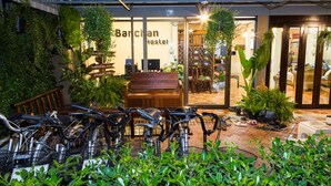 A hostel with a wooden bench, bicycles, and potted plants. - Banchan Hostel (Ayutthaya)