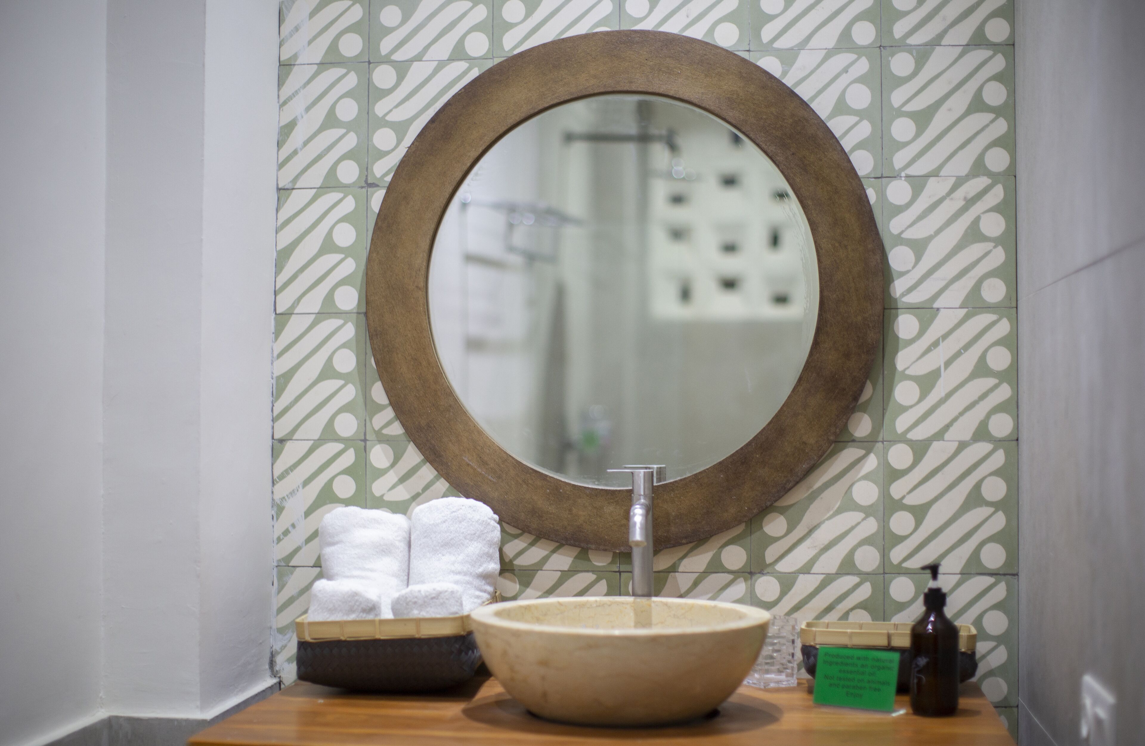 A bathroom with a round mirror, a sink, and a towel rack.