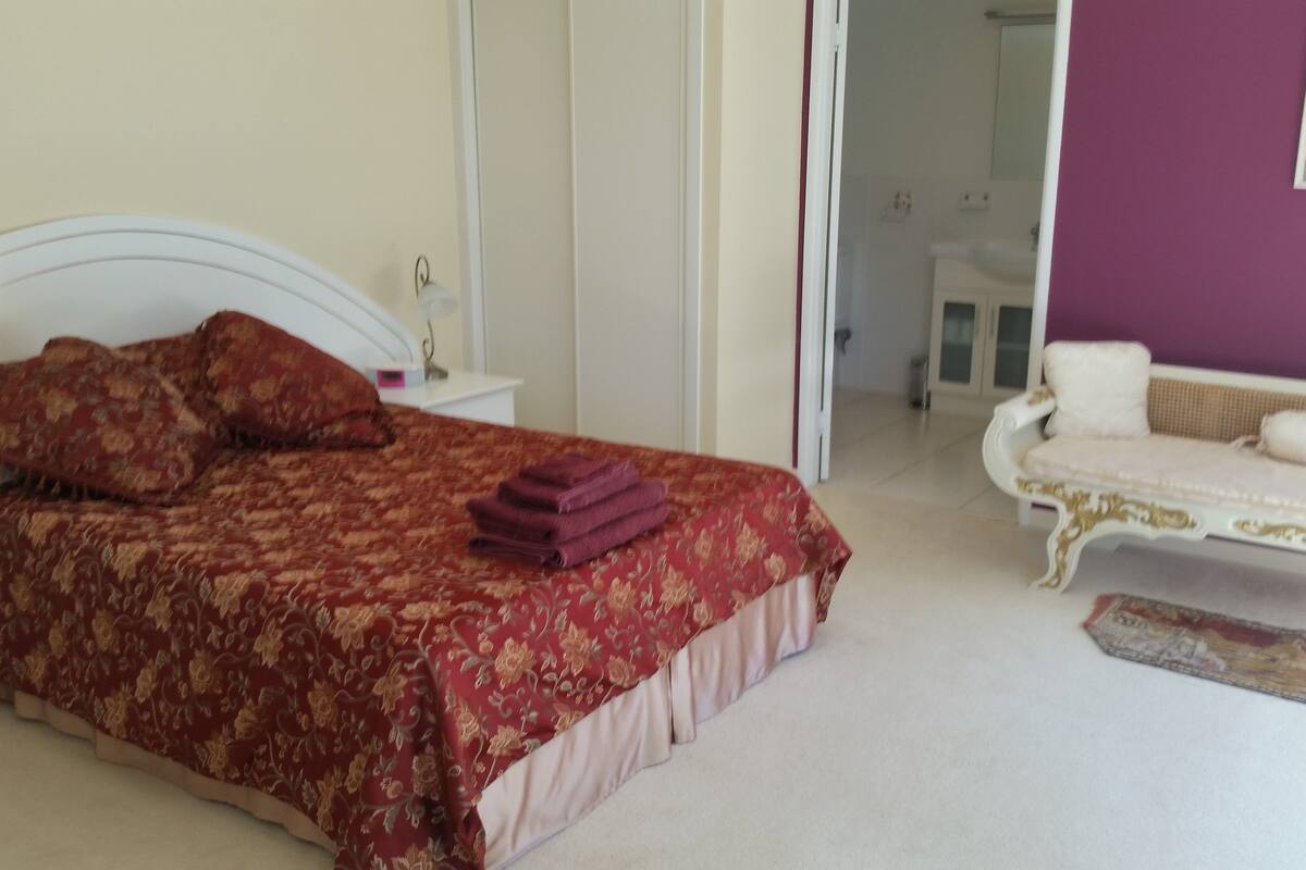 A bedroom with a bed, pillows, a nightstand, a dresser, and a chair.