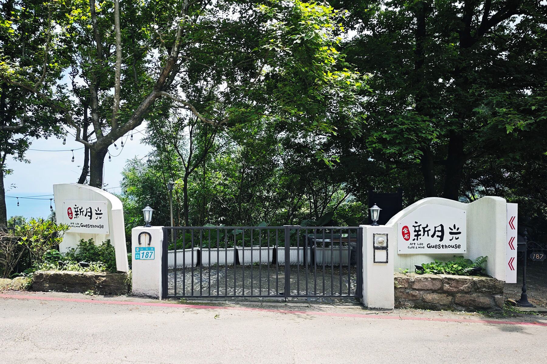 A gated entrance with a sign indicating 'Art Life Guesthouse' and a number '187'.