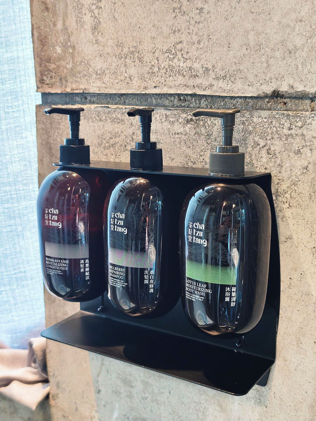 Uma prateleira no banheiro com três frascos de shampoo.