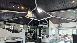 A spacious interior with a high ceiling, a central staircase, and a seating area with tables and chairs. - Gold Stone Crescent Moon Light (New Taipei City)