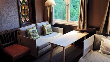 A cozy room with a sofa, a small table, a bench, and a window with curtains.