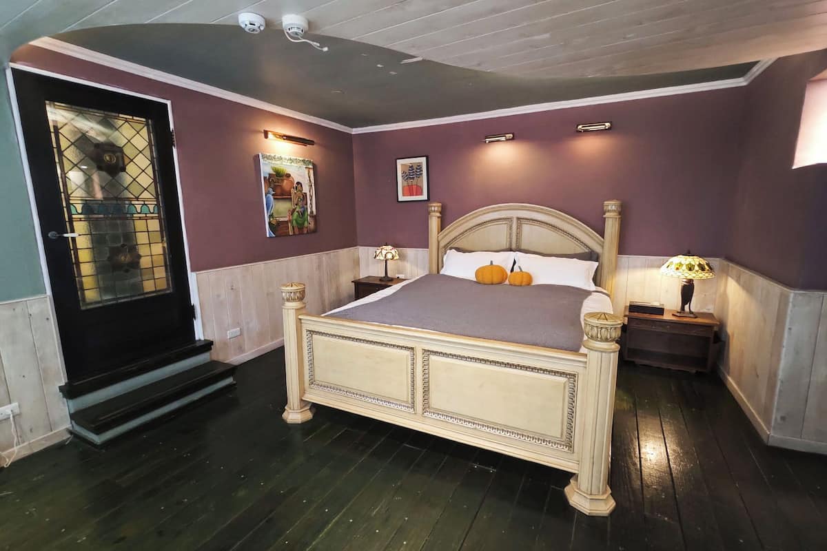 A bedroom with a wooden bed, a door with glass panels, and a ceiling with recessed lighting.