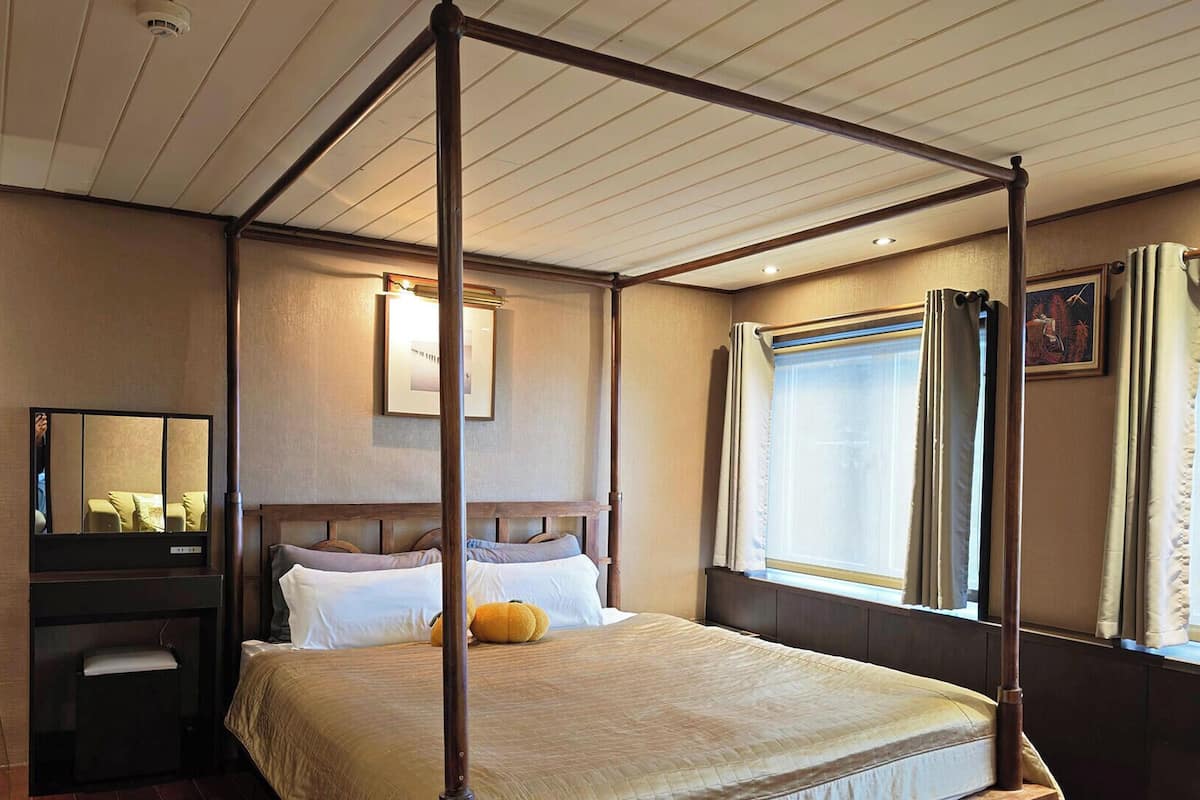 A four-poster bed with a headboard, a bedside table, and a mirror.
