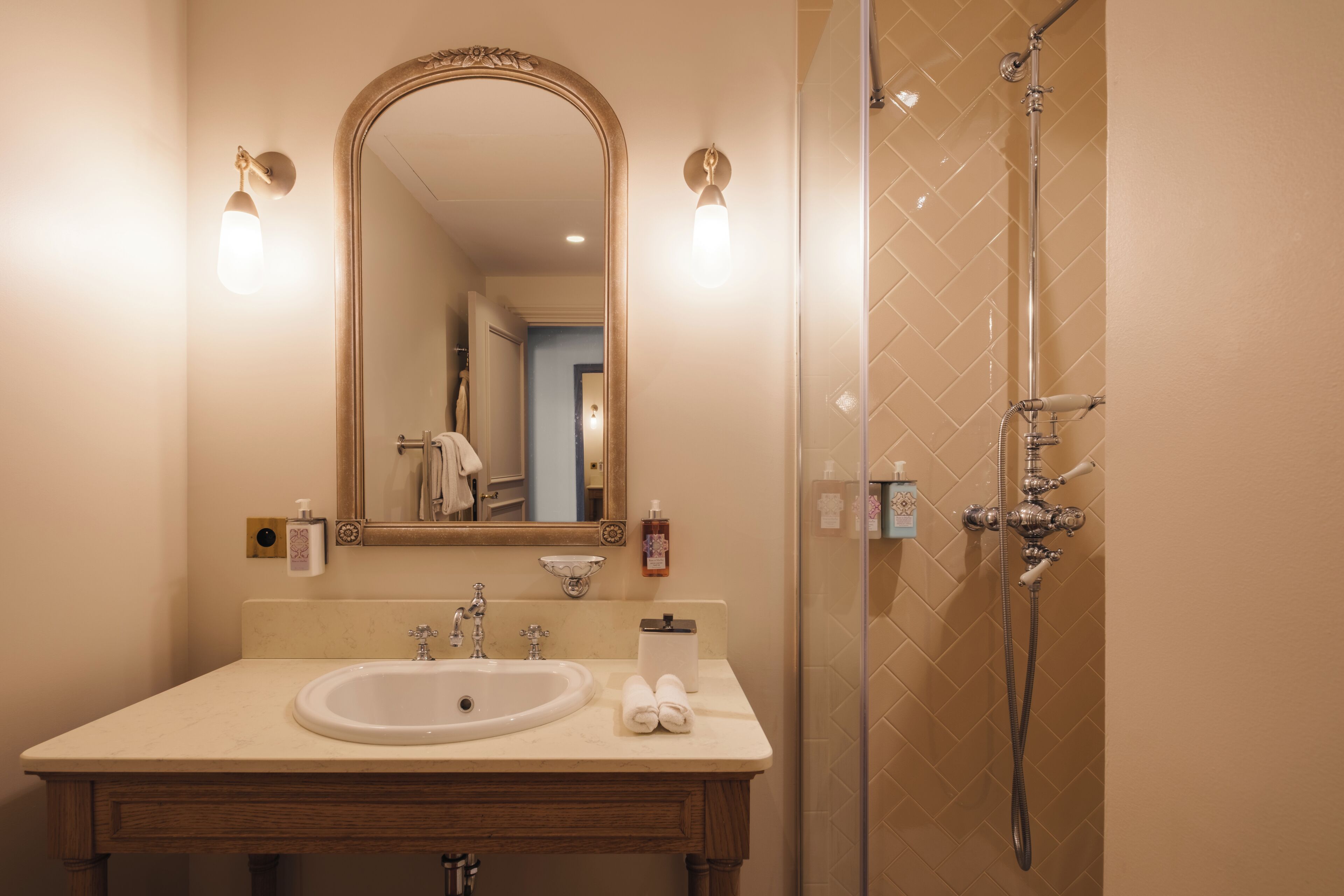 A bathroom with a sink, mirror, towel rack, and shower.