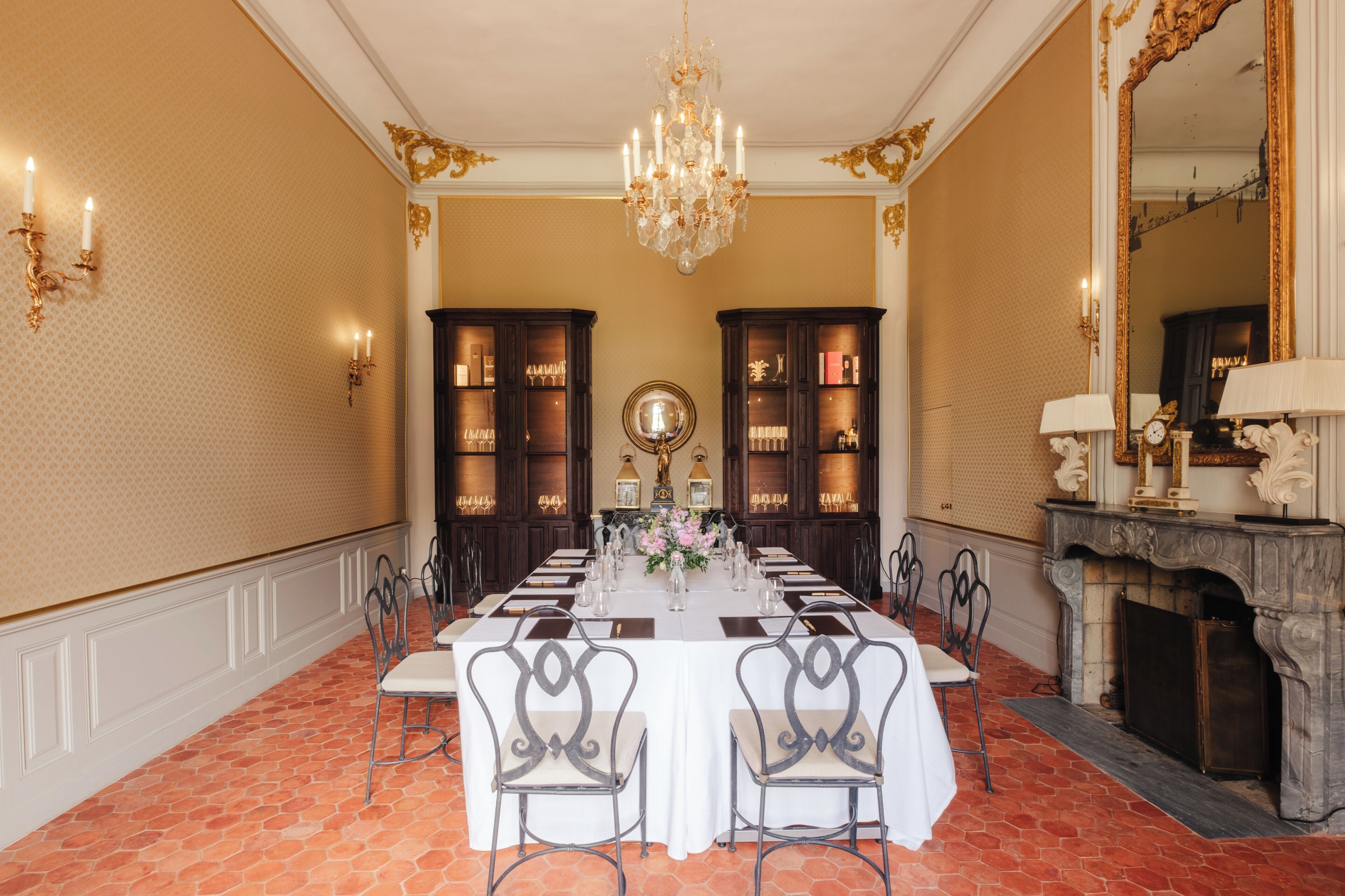 Ein formeller Speisesaal mit einem langen Tisch, der für eine Mahlzeit gedeckt ist, umgeben von Stühlen, einer Chandelier und einem Kamin.