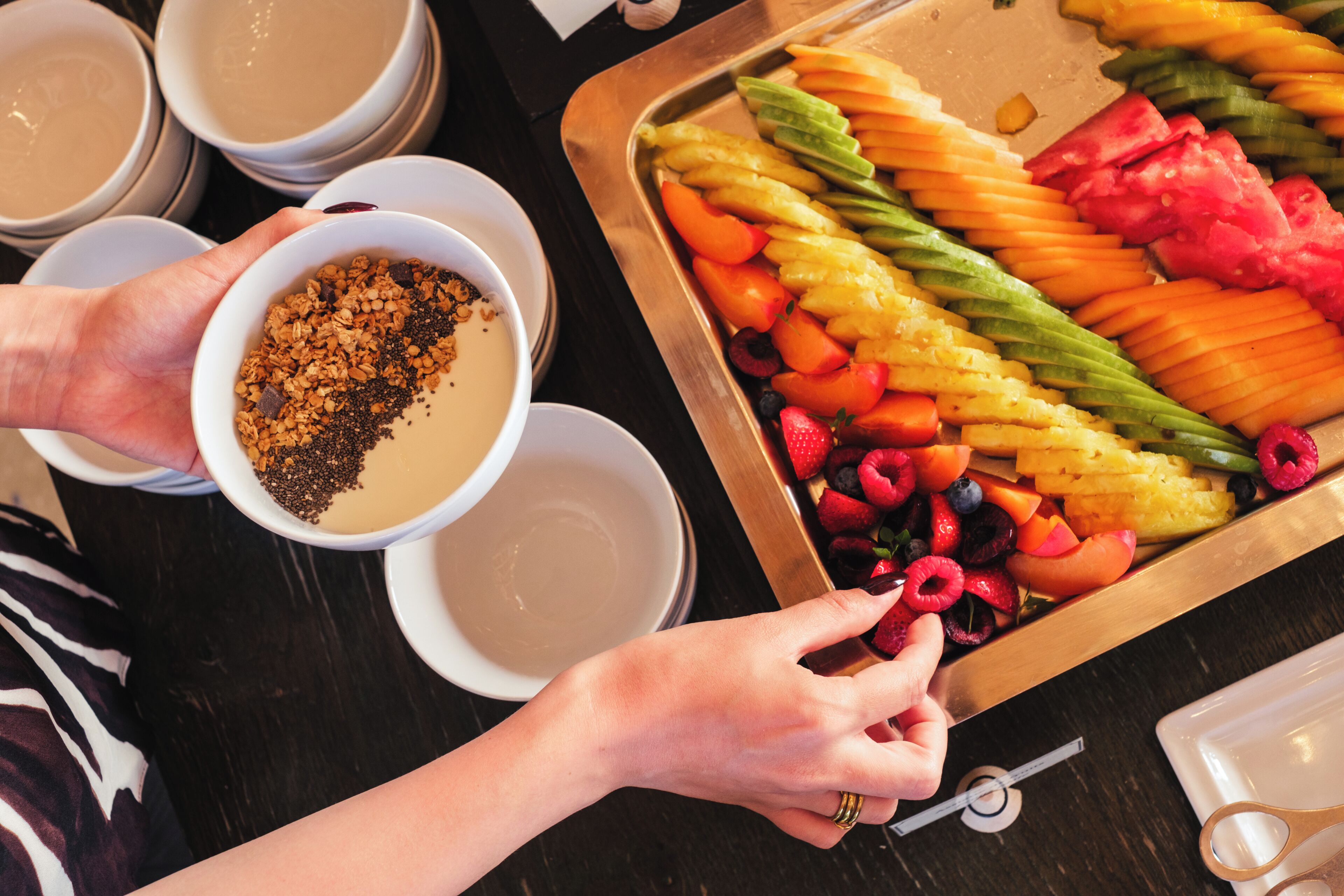 A tray of assorted fruits and a bowl of granola.