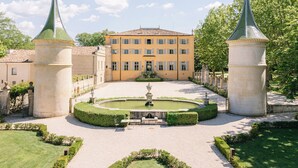 Een binnenplaats met een fontein, omgeven door een verzorgd gazon en een gebouw met een symmetrische gevel.